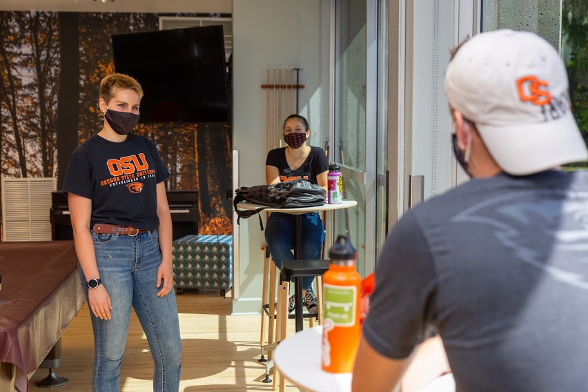 Students conversing with masks on inside a building