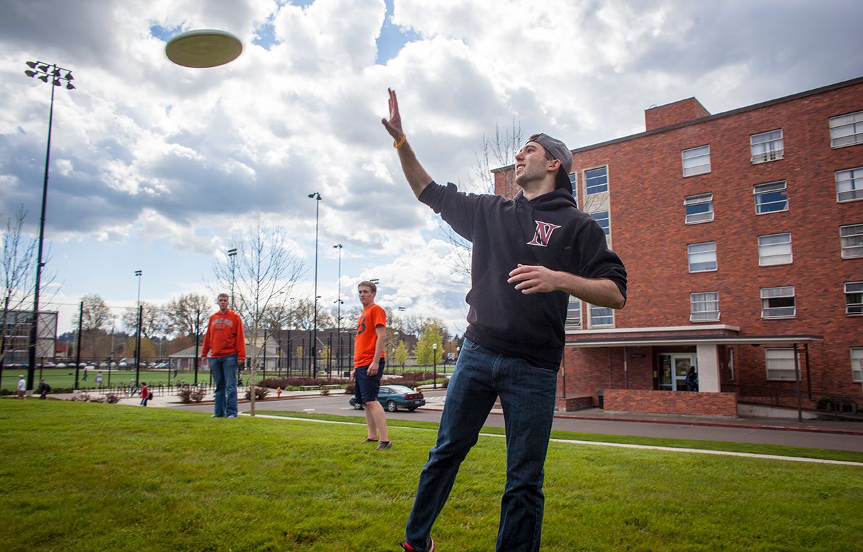Students playing frisbee outside on a sunny day