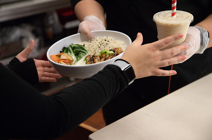 worker handing rice bowl to customer