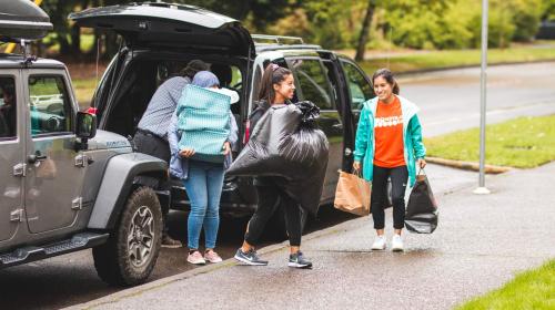 Students carrying belongings from car on campus